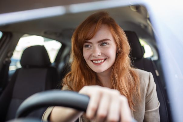 A happy business woman driving her short-term rental vehicle.